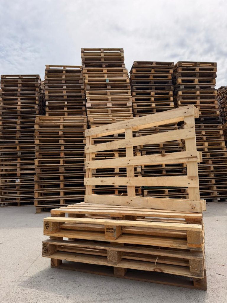 Stivă de paleți din lemn, marcați EPAL, amplasați într-un spațiu industrial exterior, cu turnuri înalte de paleți depozitați în fundal. Logistică, retail, producție